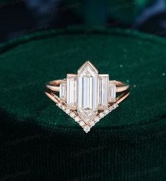 an emerald colored diamond ring on top of a green velvet bag with diamonds around it