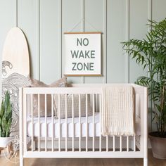 a white crib with a surfboard on the wall next to it and a sign that says no wake zone