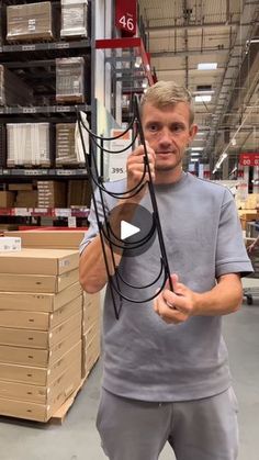 a man is holding a large piece of black wire in his hand while standing next to boxes