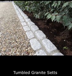 a garden with gravel and plants next to it that says tumbled granite sets