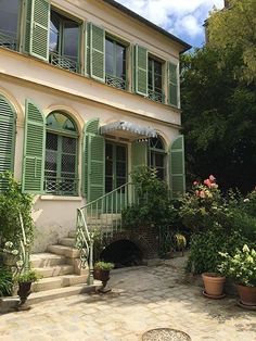 a house with green shutters and potted plants