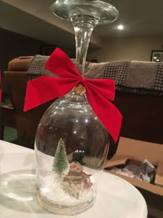 a wine glass with a red bow on it sitting on top of a white table