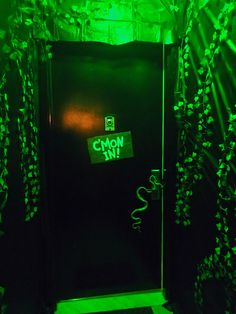 a black door with neon green writing on it and some plants growing out of it