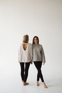 two women standing next to each other in front of a white wall with one woman's back turned towards the camera