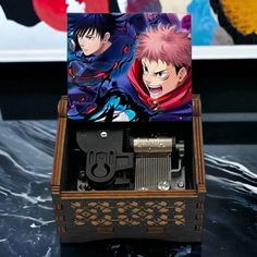 an open wooden box with two anime characters on the front and back sides, sitting on top of a black table