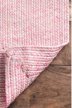 the pink and white rug is laying on top of wood flooring, with a wooden surface