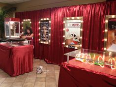 a woman standing in front of a table with candles on it and some posters behind her