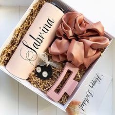 an open box containing a bottle, hair clip, and pink ribbon with the word fabulous written on it