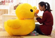 a woman sitting on the floor with a large yellow stuffed duck in front of her