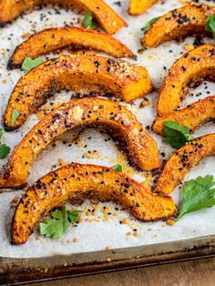 baked sweet potato wedges with herbs and seasoning on a baking sheet, ready to be eaten