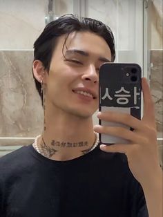 a man taking a selfie with his cell phone in front of him and wearing a necklace