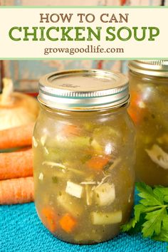 two jars filled with chicken soup sitting on top of a blue towel next to carrots