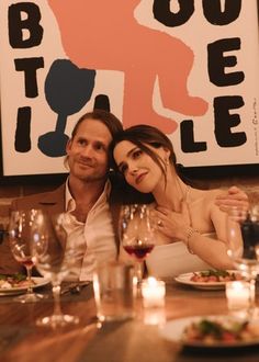 a man and woman sitting at a table with wine glasses