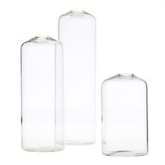 three clear glass vases sitting next to each other on a white surface with one empty bottle in the middle