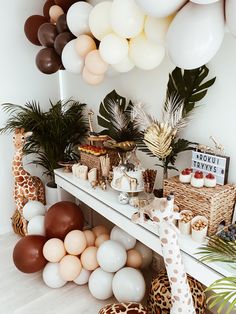 a table with balloons, giraffes and other items on top of it