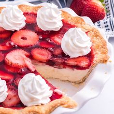 a pie with strawberries and whipped cream on top sits on a white plate next to some strawberries