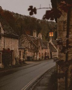 an empty street lined with stone buildings and trees in the background at dusk, surrounded by greenery