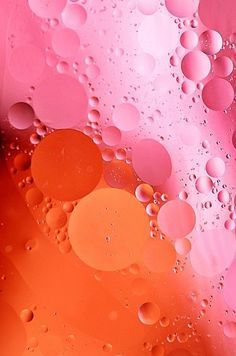 an orange and pink background with water droplets on the bottom, as well as some red circles