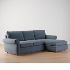 a blue sectional sofa sitting on top of a hard wood floor next to a white wall