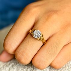 a close up of a person's hand holding a ring with a diamond on it