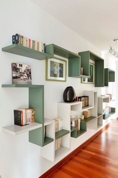 a living room filled with lots of green bookshelves next to a window and wooden floors