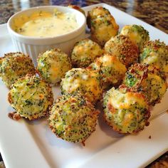 broccoli and cheese bites on a white plate with a bowl of dipping sauce