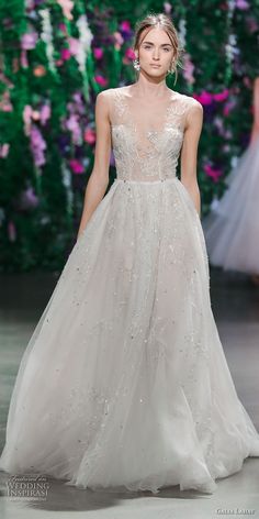 a model walks down the runway in a wedding dress with sheer tulle and beading