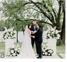 a bride and groom standing in front of their wedding ceremony arch with white flowers on it