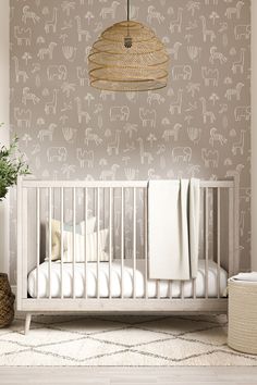 a baby crib in front of a wall with elephants on it and a basket hanging from the ceiling