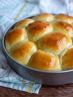 a metal pan filled with rolls on top of a wooden table