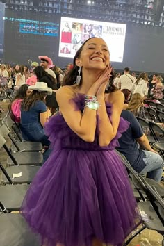 a woman in a purple dress is smiling and looking up at the sky with her hands on her face