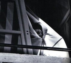 a black and white photo of a person sleeping in a chair with a blanket over their head