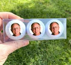 a person holding up three magnets with pictures on them in front of some grass