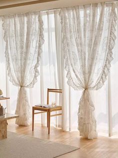 a chair sitting in front of a window with sheer curtains