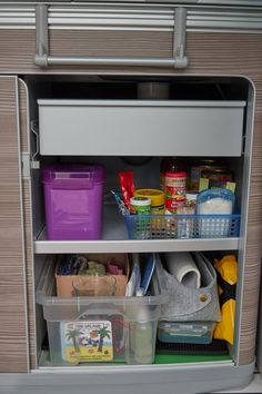 an open refrigerator filled with lots of food and containers next to plastic containers on the floor