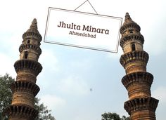 there is a sign that says juhla minara ahamediaad hanging from the side of two tall towers