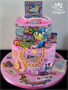 a pink cake with lots of stickers on it's top and bottom tier