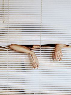 a woman's hand is peeking out from behind the blinds