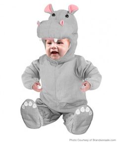 a baby is wearing a rhino costume and sitting on the floor with its mouth open