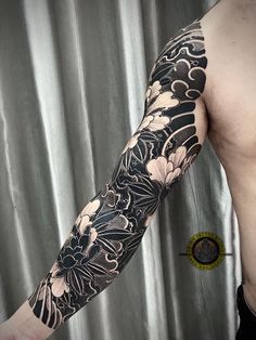 a man's arm with black and white flowers on the left side of his body