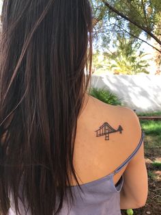 the back of a woman's shoulder with a small tattoo on her left arm