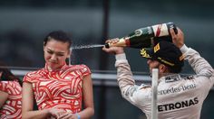 a woman in a red and white dress is spraying champagne on the head of a man