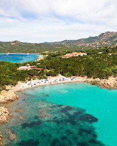 an aerial view of the beach and ocean with people on it, surrounded by trees