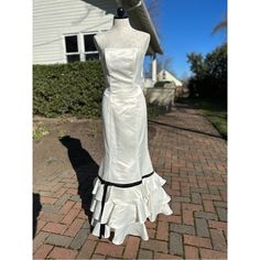 a white dress on display in front of a house with blue sky and clouds behind it