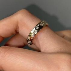 a close up of a person's hand wearing a ring with diamonds on it