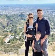 two adults and a child posing for a photo on top of a hill with the city in the background