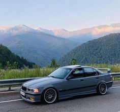 a car is driving down the road in front of mountains