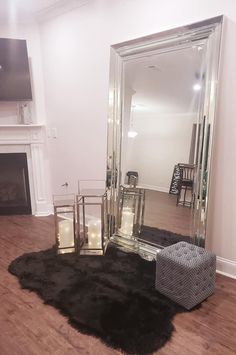 a large mirror sitting on top of a wooden floor next to a chair and fireplace