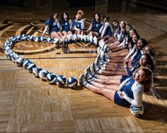 a group of cheerleaders sitting on top of a basketball court with their legs in the air