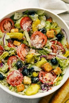 a salad with tomatoes, olives, cucumbers and parmesan cheese